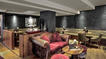 Ein stilvolles Restaurant mit gemütlichen Sitzgelegenheiten und modernem Design. Die warme Beleuchtung schafft eine einladende Atmosphäre.
