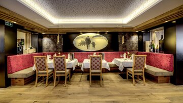 Ein elegantes Restaurant mit gemütlichen Sitzplätzen und stilvollen Tischdecken. Die warmen Farben und das moderne Design schaffen eine einladende Atmosphäre.