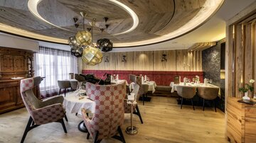 Ein elegantes Restaurant mit modernen Stühlen und stilvollem Dekor. Die Holzdecke und das sanfte Licht schaffen eine gemütliche Atmosphäre.