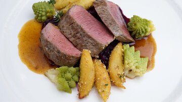 Ein Gericht mit perfekt zubereitetem Rinderfilet, serviert mit goldenen Kartoffelspalten und grünen Romanesco. Darüber liegt eine aromatische Sauce.