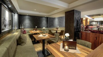 Eine moderne Restaurant-Atmosphäre mit gemütlichen Sitzbänken und Holztafeln. Die Beleuchtung ist sanft und schafft eine einladende Stimmung.