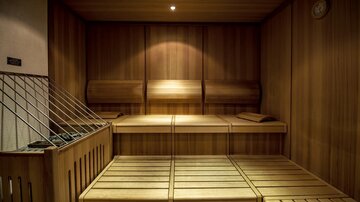 Ein gemütlicher Saunaraum aus Holz mit Bänken zum Entspannen. Warmes Licht schafft eine entspannende Atmosphäre.