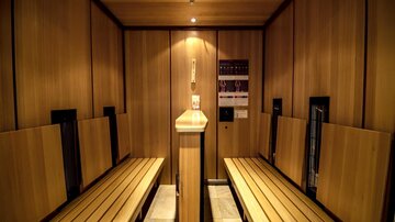 Eine moderne Sauna mit Holzverkleidung und Bänken zum Entspannen. Sanftes Licht schafft eine ruhige Atmosphäre.