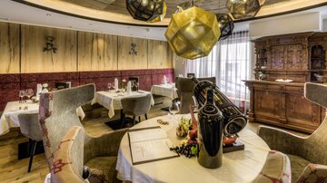 Ein stilvolles Restaurant mit komfortablen Stühlen und eleganter Beleuchtung. Die Einrichtung ist modern und gemütlich, mit Holzwänden und dekorativen Elementen.