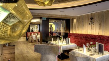 Ein elegantes Restaurant mit moderne Möbeln und warmen Holztönen. Der Raum ist stilvoll dekoriert und bietet eine gemütliche Atmosphäre.