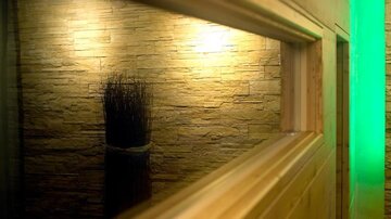 A modern wall with a stone look and soft lighting. In the foreground, there is a decorative element made of dry branches.