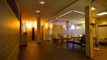A modern fitness area with elegant lighting and cozy seating. The wooden and stone surfaces give the space a warm atmosphere.