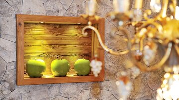 Ein dekorativer Kasten mit drei grünen Äpfeln auf einer Holzwand. Im Hintergrund ist ein Kristalllüster zu sehen.