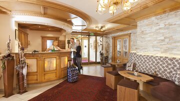 An inviting reception area with a wooden counter and cozy seating. The atmosphere is bright and friendly, ideal for guest arrivals.