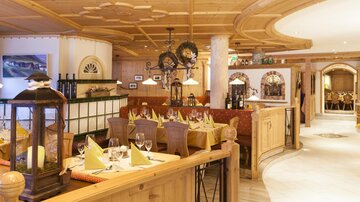 A cozy restaurant with wooden decor and elegant tables. The atmosphere is warm and inviting.