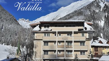 Ein elegantes Hotel in den Bergen, umgeben von schneebedeckten Tannen. Klare blaue Himmel und majestätische Berge sorgen für eine malerische Kulisse.