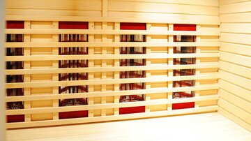 Ein heller Saunaraum mit Holzverkleidung und elektrisch betriebenen Infrarotstrahlern. Die Wände sind schlicht und laden zur Entspannung ein.