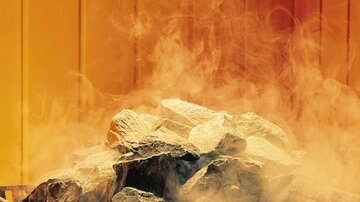 Ein Haufen steinerner Felsen mit aufsteigendem Rauch. Die Farben im Hintergrund sind orange und gelblich.
