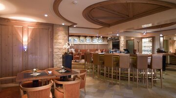 Ein elegantes Restaurant mit Holzverkleidung und einer gemütlichen Bar. Die Atmosphäre ist einladend und modern.